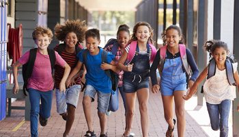 School kids running in elementary school hallway, front view